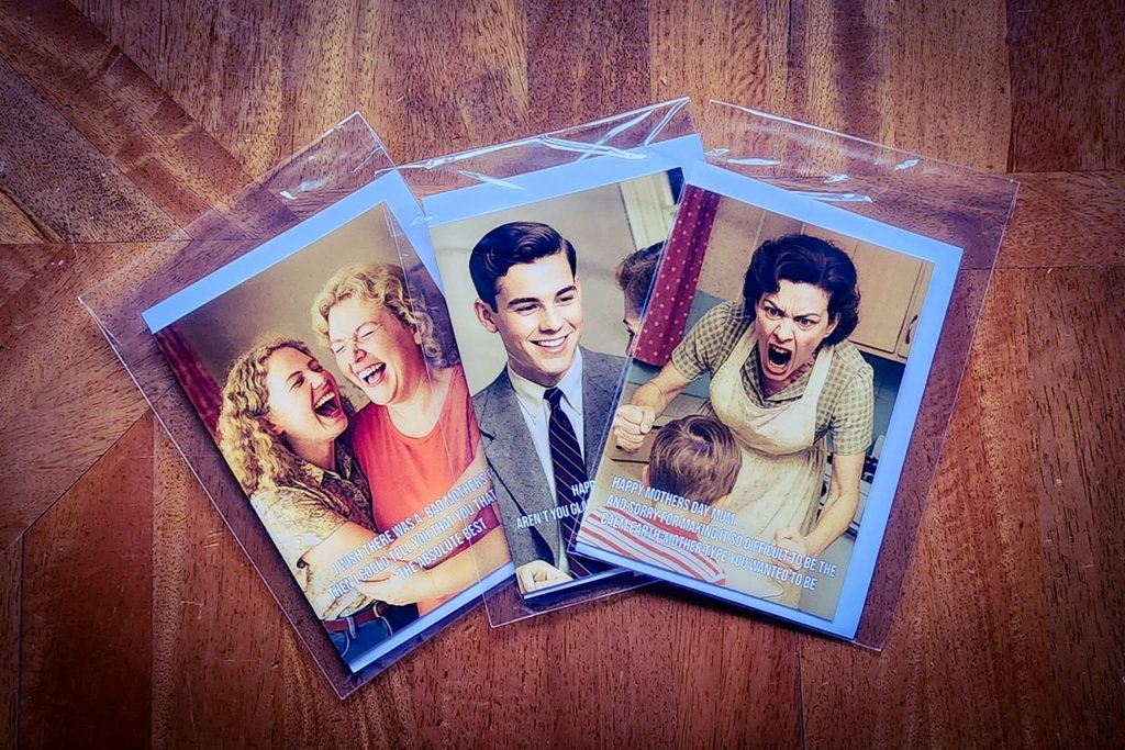 A selection of funny cards from savagemedia.nz fanned out on the table.